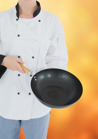 Digital composite of Chef with wok against blurry yellow backgroundの写真素材