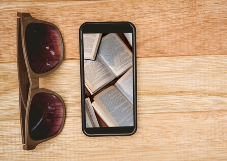Digital composite of Sunglasses and phone showing open booksの写真素材