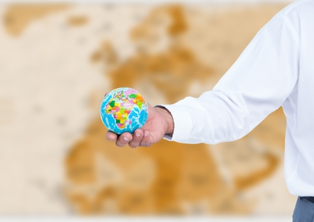 Digital composite of Arm with globe against blurry brown mapの写真素材