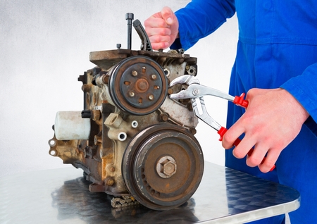 Digital composite of Mechanic working on machine against white wall