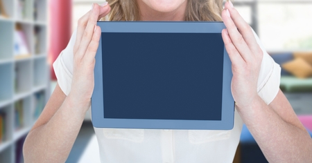Digital composite of Womans hands holding tablet in Libraryの写真素材