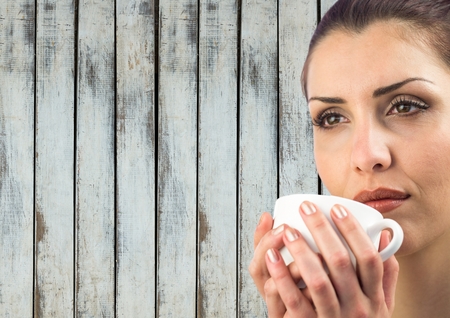 Digital composite of Close up of woman drinking from white cup against wood panelの写真素材