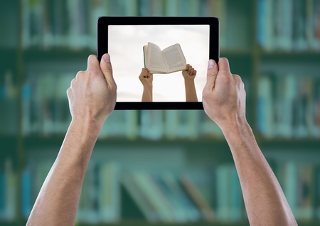Digital composite of Hand with tablet showing hands with book against blurry bookshelf with green...