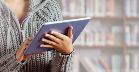 Digital composite of Woman on tablet in Libraryの写真素材