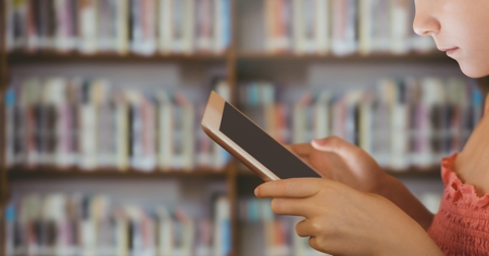Digital composite of girl on tablet in Libraryの写真素材