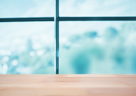 Digital composite of Wood table against blurry blue windowの写真素材