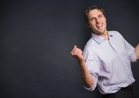 Digital composite of Man in lavender shirt holding up fist against navy chalkboardの写真素材