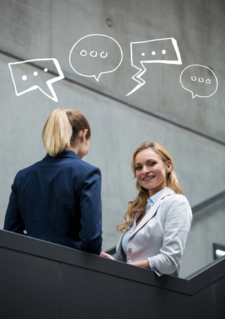 Digital composite of Business women on stairs with white speech bubblesの写真素材
