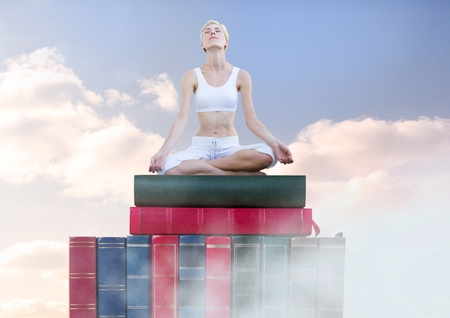 Digital composite of Woman meditating relaxing on Books stacked by skyの写真素材