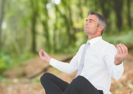 Digital composite of Businessman Meditating by forestの写真素材