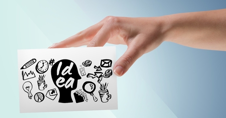 Digital composite of Hand with card and black idea doodles against blue backgroundの写真素材