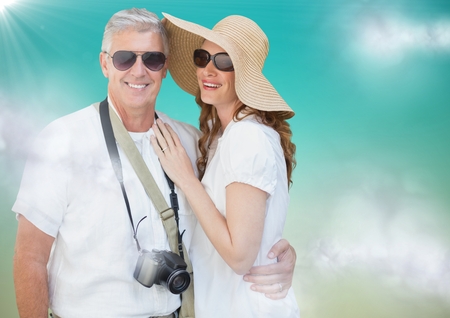 Digital composite of Couple in summer clothes against blue green background with clouds and flareの写真素材