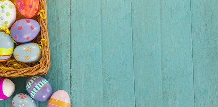 Various Easter eggs arranged in wicker basket on wooden surfaceの写真素材