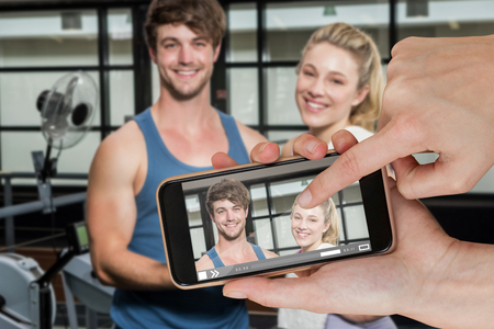 Hands touching smart phone against portrait of trainer and woman standing with digital tablet