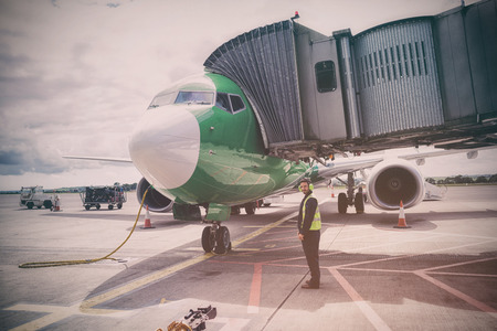 Mechanic standing against airplane at runwayの写真素材