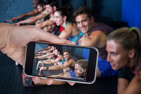 Composite image of hand holding mobile phone against white backgroundの写真素材