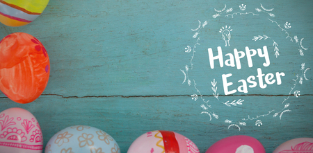 Happy Easter red logo against a white background against various easter eggs arranged on wooden surfaceの写真素材