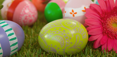 Painted easter eggs with pink flower on grassの写真素材