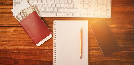 Pen on notepad next to keyboard and smaprtphone on wooden table