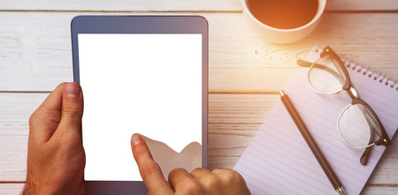 Cropped image of person using tablet at desk next to various objectsの写真素材