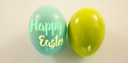 Happy easter logo against blue and green easter eggs on white backgroundの写真素材
