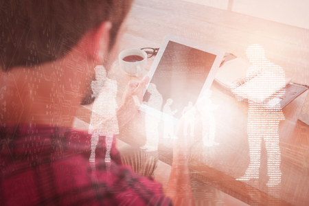 Man using tablet on wooden table against shiny silhouettes on blue backgroundの写真素材