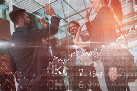 Stocks and shares against group of happy businesspeople giving high five to each otherの写真素材