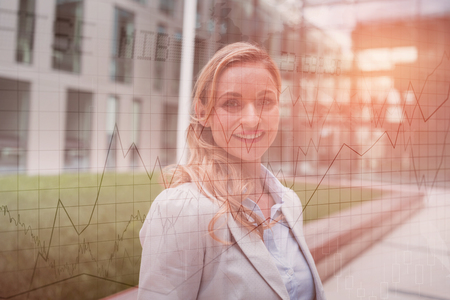 Stocks and shares against smiling businesswoman standing in office premisesの写真素材