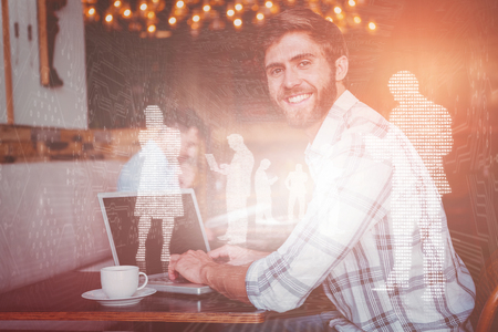 Shiny silhouettes on blue background against young man working on his computerの写真素材
