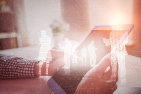 Shiny silhouettes on blue background against hand using tabletの写真素材