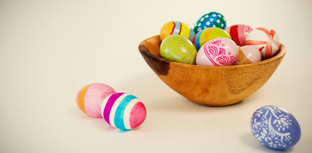 Colorful Easter eggs in wooden bowl on white background