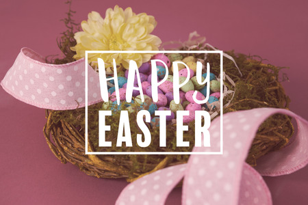 Easter greeting against colorful easter eggs in wicker basket with a flower