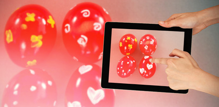 Hands touching digital tablet against white background against red easter eggs on gray backgroundの写真素材