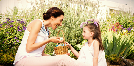 Mother and daughter collecting easter eggs outside in the gardenの写真素材