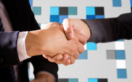 Male and female corporates shaking hands against technical background with squarsの写真素材