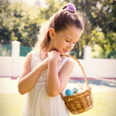 Little girl collecting easter eggs outside in the gardenの写真素材