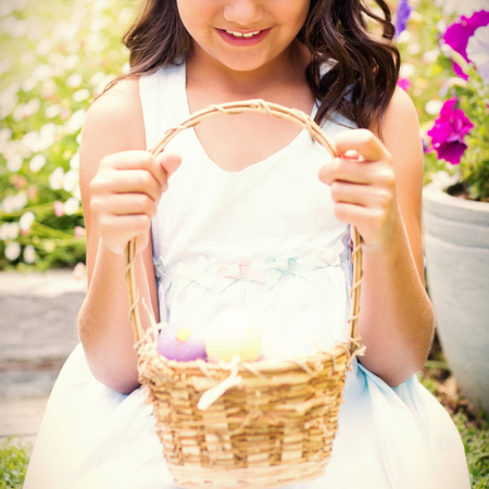 Happy girl collecting easter eggs in the gardenの写真素材