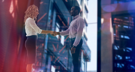 Corporate man and woman doing handshake against exterior of modern buildingの写真素材