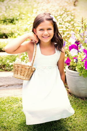 Happy girl collecting easter eggs in the gardenの写真素材