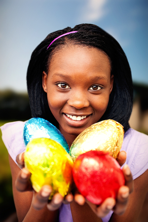 Muddy road by grassy field against attractive woman holding colorful easter eggsの写真素材