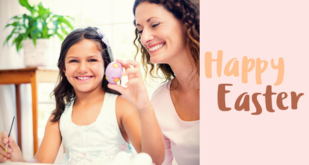 Happy mother and daughter painting easter eggs  against beige backgroundの写真素材