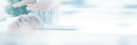 Therapist performing Reiki over senior man at spaの写真素材