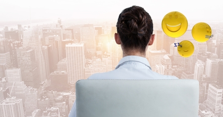 Digital composite of Back of business woman in chair with emojis against blurry skylineの写真素材