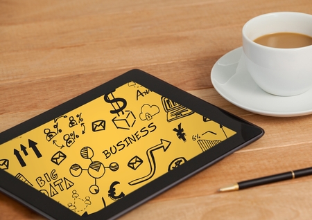 Digital composite of Tablet on table with coffee showing black business doodles and yellow backgroundの写真素材