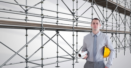 Digital composite of engineer with the hat on his arm in front of 3D scaffoldingの写真素材