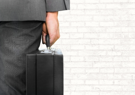 Digital composite of Businessman with briefcase facing white wallの写真素材