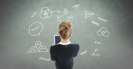 Digital composite of Businesswoman using tablet PC with various apps drawn on backgroundの写真素材