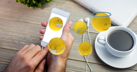 Digital composite of Cropped image of man using smart phone with various emojisの写真素材