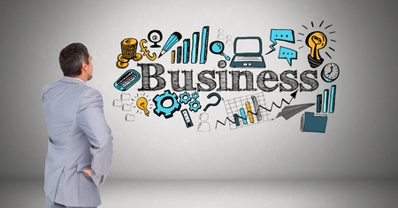 Digital composite of Businessman looking at business text with various icons against gray backgroundの写真素材