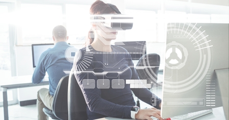 Digital composite of Businesswoman wearing VR glasses while using computer in officeの写真素材